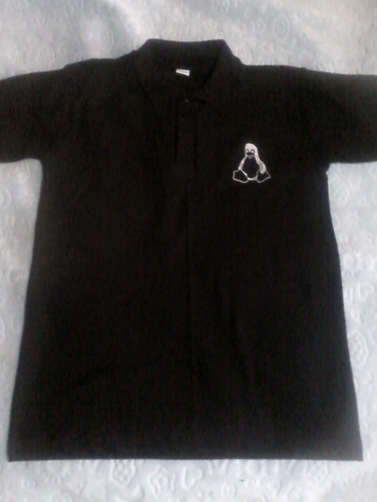 Embroidered black polo shirt front with white thread used to embroider Tux