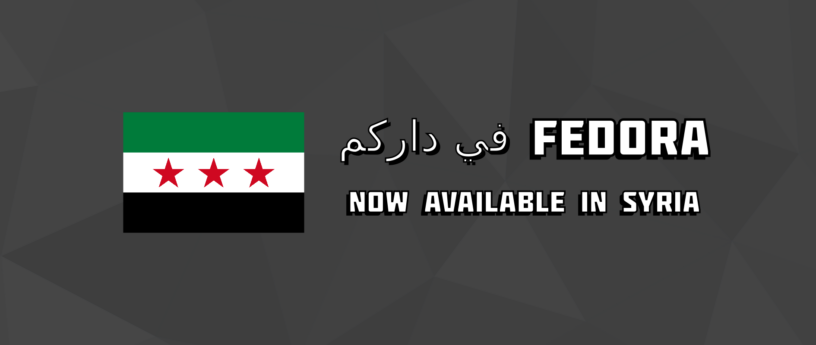 A dark grey banner featuring the Syrian Independence flag alongside the text "Now available in Syria", "Fedora", and the Syrian Arabic phrase "في داركم" below it. The background has a subtle triangular pattern.