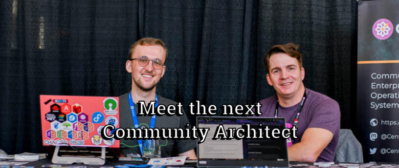 Two men sit behind laptops at a booth with large overlaid text reading, "Meet the next Community Architect". The background consists of black drapes and a partial event banner.